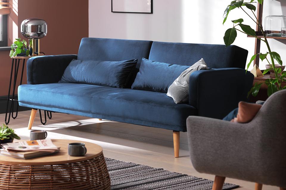 Blue color sofa chair bed with brown legs with the table in the living room